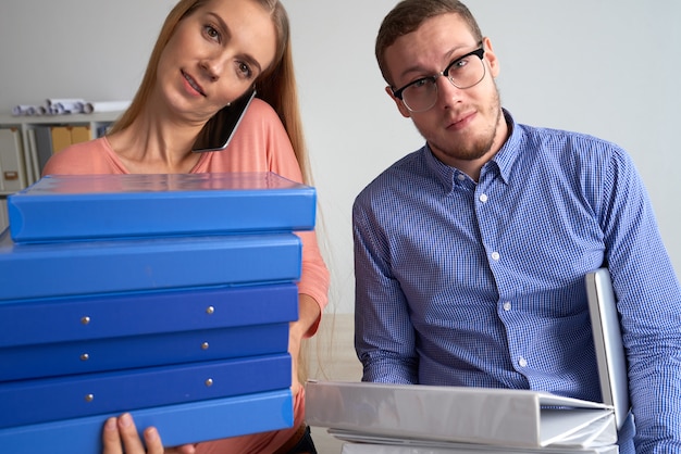 Photo gratuite gros plan moyen de deux collègues ayant une charge de travail importante chargée de plusieurs dossiers de documentation