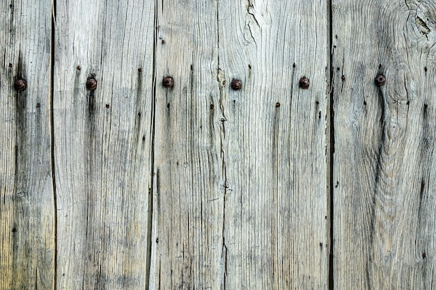 Gros plan d'un mur en bois gris avec des clous dessus