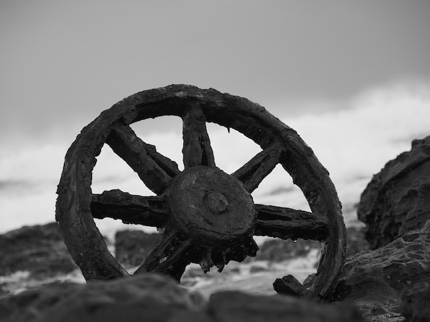 Photo gratuite gros plan en niveaux de gris d'une vieille roue rouillée entourée de pierres