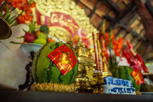 Gros plan d'une pastèque sur l'autel des ancêtres pendant les vacances du têt au vietnam. texte doré sur papier en photo signifiant paisible. mise au point sélective.