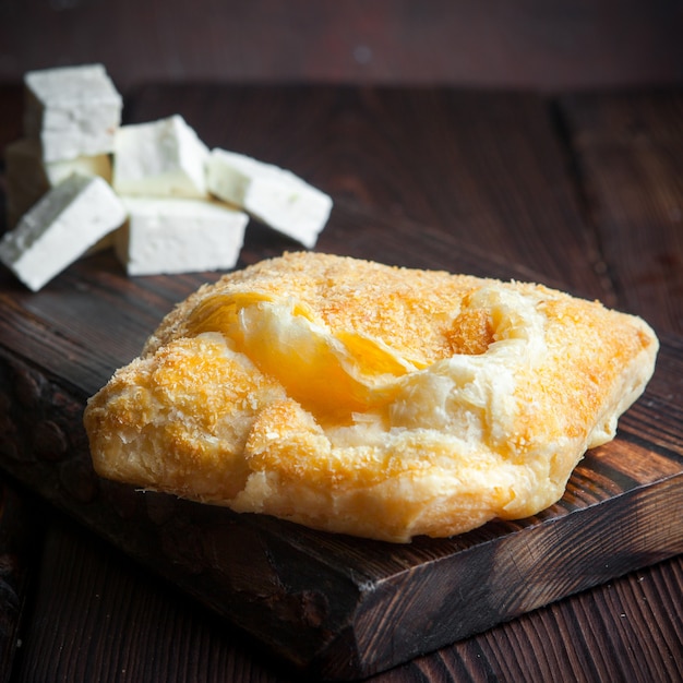 Gros plan de pâte feuilletée sur planche de bois avec du fromage