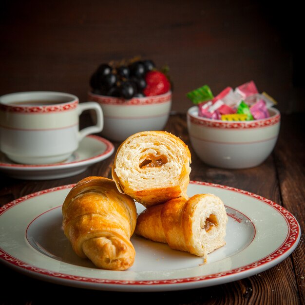 Gros plan de pâte feuilletée avec une tasse de thé, des bonbons et des baies sur table en bois