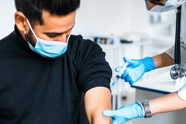 Gros Plan Sur Un Patient Vacciné, Le Médecin Injecte Un Vaccin Contre Le Coronavirus Dans La Main Du Patient.