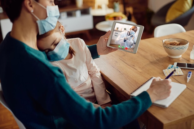 Gros plan d'un pédiatre noir conseillant sa mère lors d'un appel vidéo sur un pavé tactile