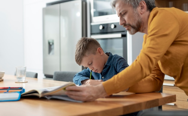 Gros plan père aidant enfant à faire ses devoirs