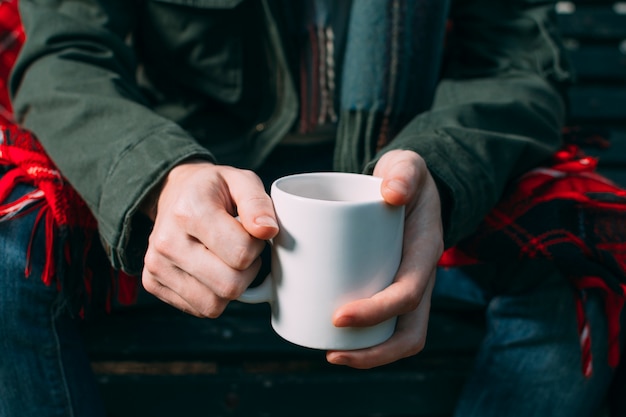 Photo gratuite gros plan personne brandissant une tasse blanche