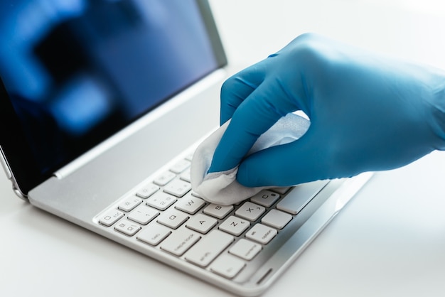 Photo gratuite gros plan d'une personne désinfectant le clavier d'un ordinateur portable