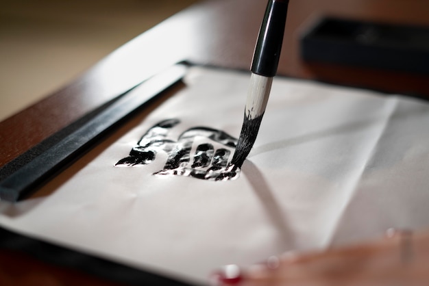 Gros plan sur une personne faisant de la calligraphie japonaise, appelée shodo
