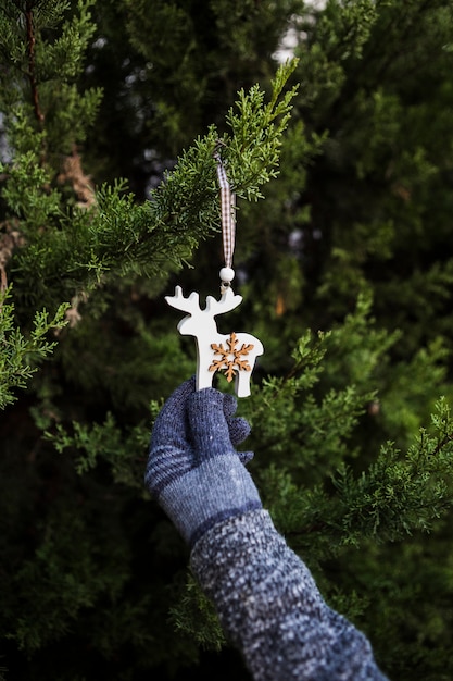 Gros plan personne avec des gants tenant une décoration en forme de renne