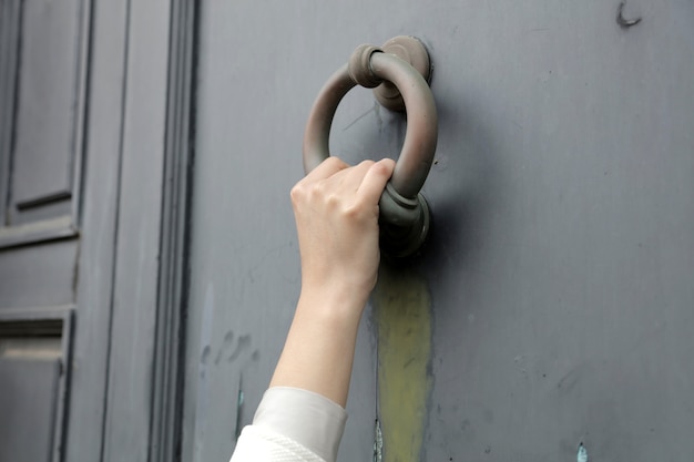 Photo gratuite gros plan d'une personne qui frappe à la porte avec un vieux heurtoir de porte