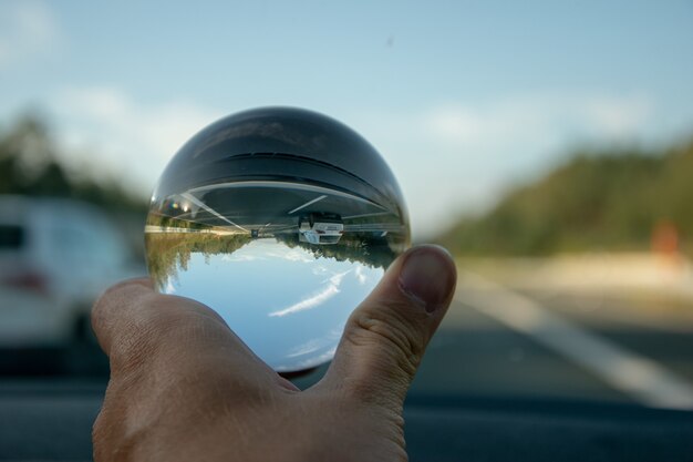 Gros plan d'une personne tenant une boule de cristal avec le reflet des arbres