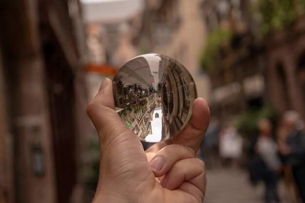 Gros plan d'une personne tenant une boule de cristal avec le reflet de bâtiments historiques