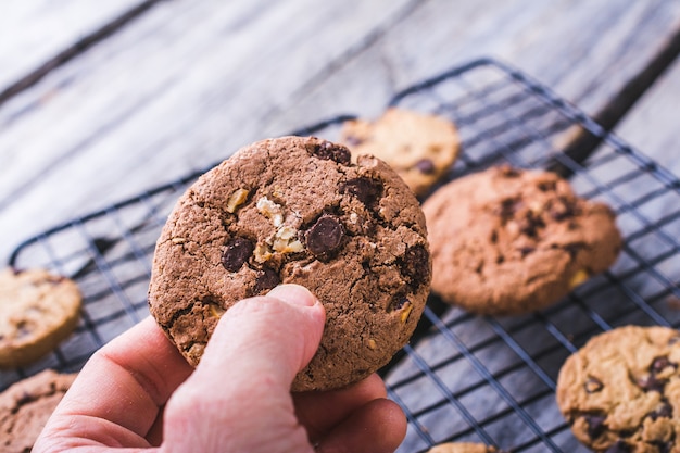 Gros plan d'une personne tenant un cookie aux pépites de chocolat sur un arrière-plan flou