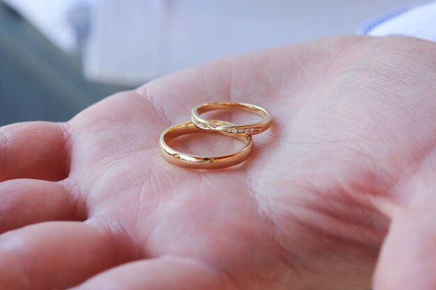 Gros plan d'une personne tenant deux anneaux de mariage en or