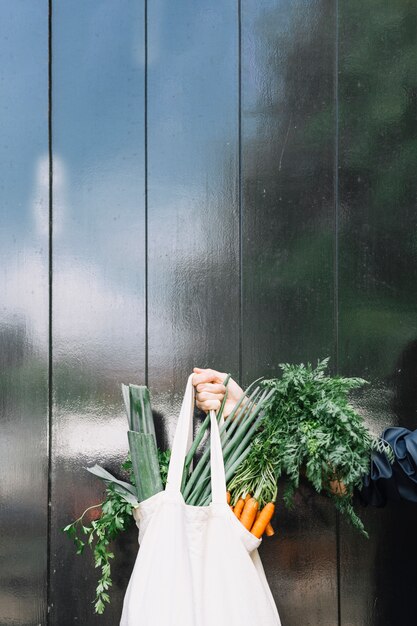 Gros plan, de, a, personne, tenue, sac, de, légumes feuilles, contre, noir, bois, mur