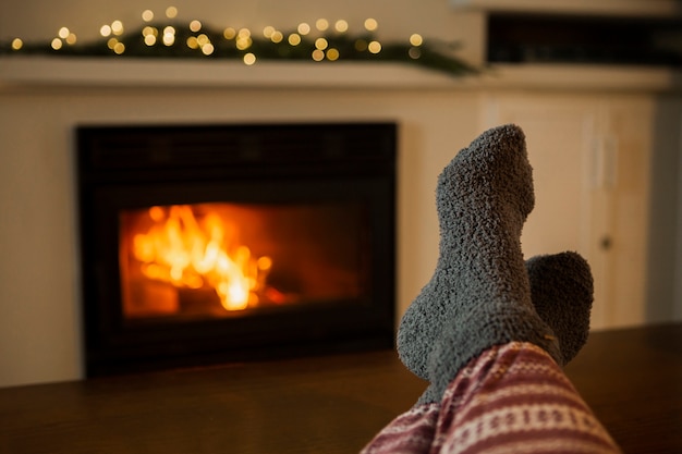 Gros plan personne avec des vêtements confortables près de la cheminée