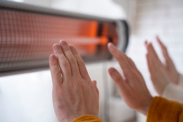 Gros plan des personnes se réchauffant les mains près du radiateur