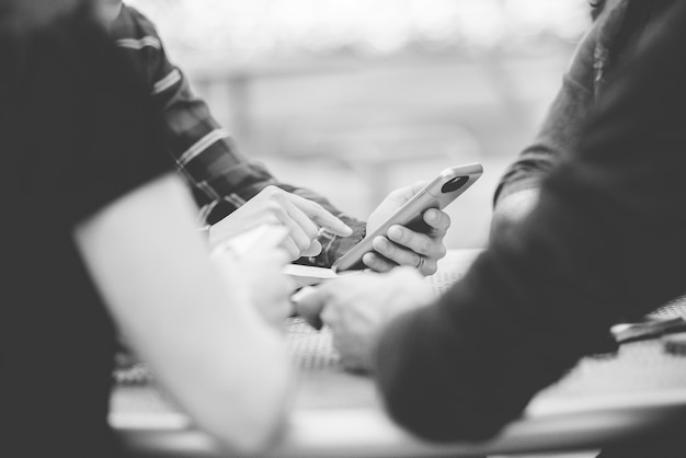 Photo gratuite gros plan de personnes utilisant leur smartphone avec un arrière-plan flou en noir et blanc