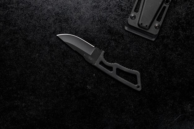 Gros plan d'un petit couteau tranchant avec une poignée noire sur fond noir