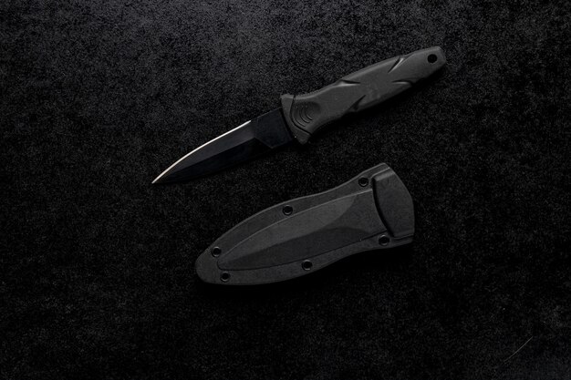 Gros plan d'un petit couteau tranchant avec une poignée noire sur un tableau noir