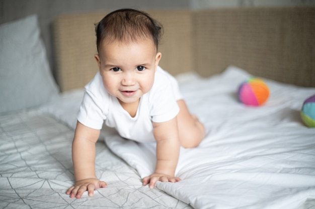 Gros plan d'un petit enfant joyeux sur le lit sous les lumières dans une chambre