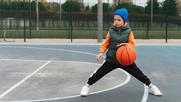 Photo gratuite gros plan sur un petit garçon jouant au basket