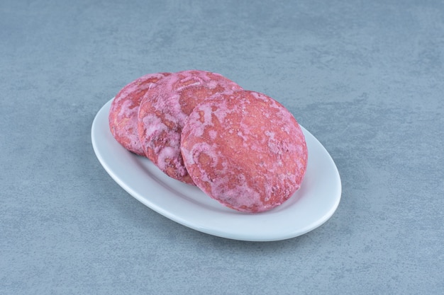 Gros plan photo de biscuit rose frais fait maison sur plaque blanche.