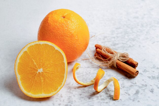 Gros plan photo d'une orange fraîche à moitié coupée ou entière avec de la cannelle.