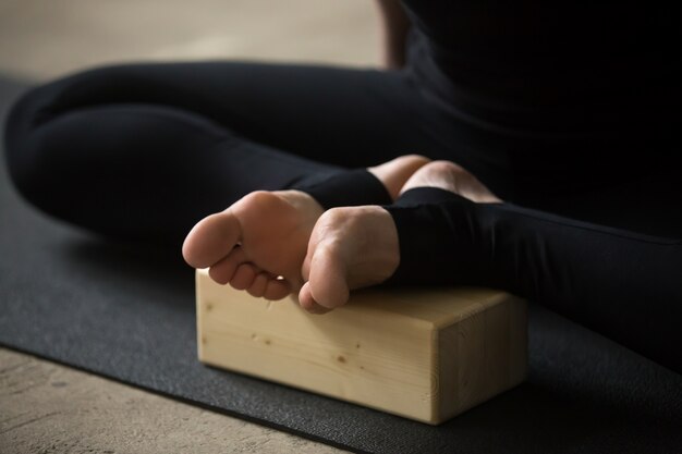 Gros plan des pieds féminins en pose papillon avec bloc, studio