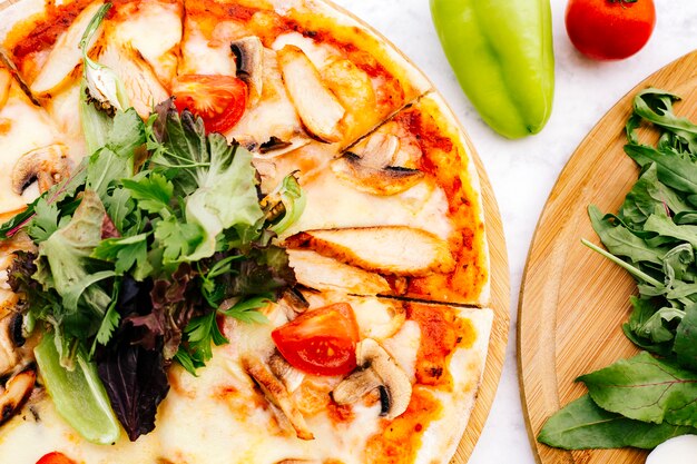 Gros plan de pizza au poulet avec tomate aux champignons garnie d'herbes