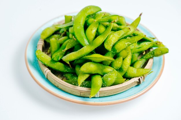 Gros plan d'une plaque d'edamame salé sur fond blanc