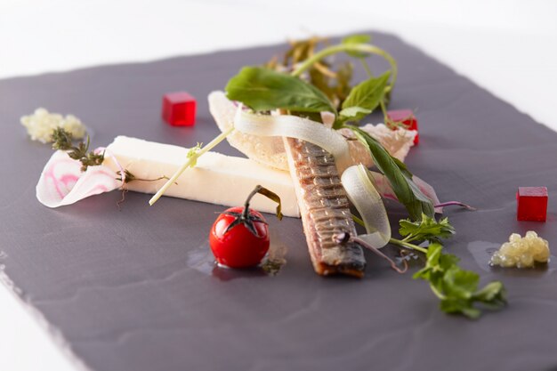 Gros plan d'un plat savoureux avec du poisson et des légumes sur une surface noire