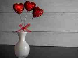 Photo gratuite gros plan d'une pop décorative en forme de coeur rouge dans un vase sur un fond gris