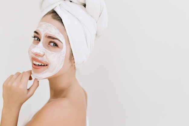 Gros plan portrait de la belle jeune femme avec des serviettes après prendre le bain faire un masque cosmétique sur son visage.