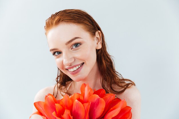 Gros plan le portrait d'une femme rousse tenant des fleurs de tulipe