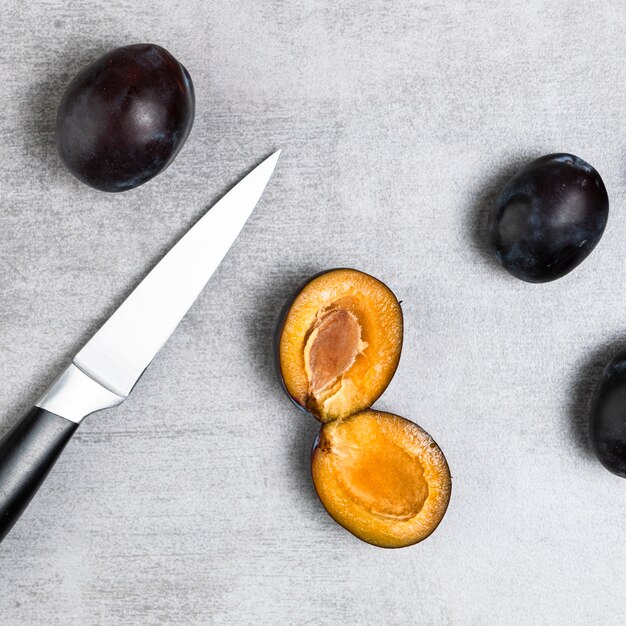 Gros plan de prunes et couteau sur une table en bois