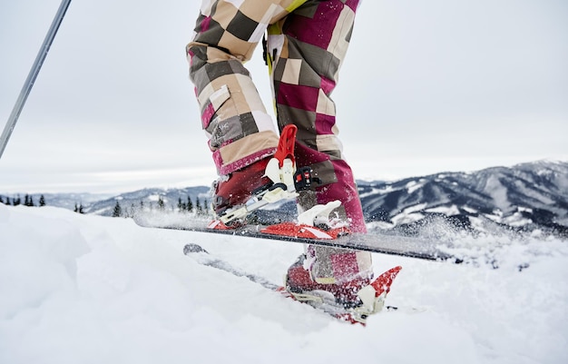 Gros plan recadré des jambes du skieur fixation de ski et skis faisant un pas en avant