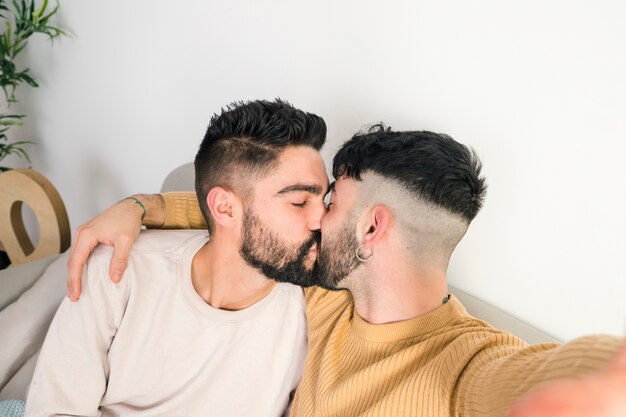 Gros plan, romantique, jeune couple gay, s&#39;embrasser, prenant, selfie