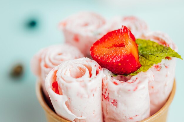Gros plan des rouleaux de crème glacée aux fraises dans le récipient