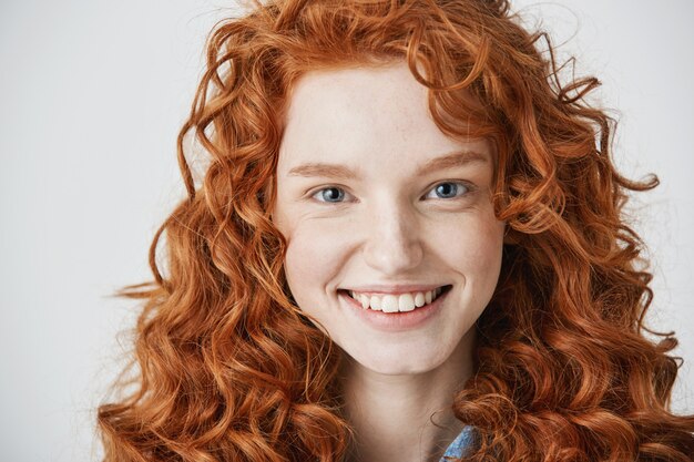 Gros plan d'une rousse belle femme avec des taches de rousseur souriant.