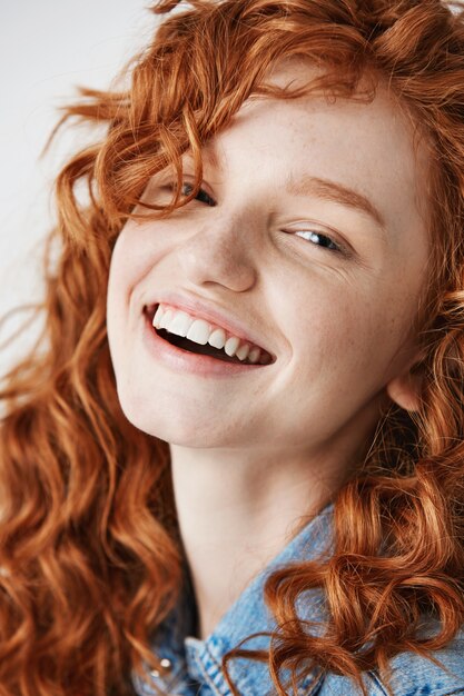 Gros plan d'une rousse belle fille avec des taches de rousseur souriant.