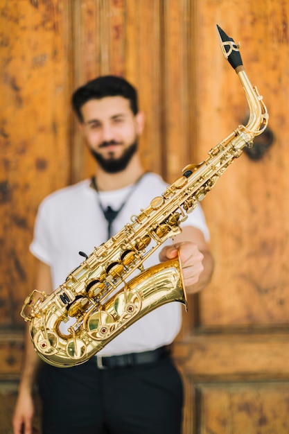 Photo gratuite gros plan saxophone tenu par un musicien défocalisé