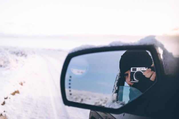 Gros plan sélectif d'une personne avec des gants et un chapeau tenant un appareil photo