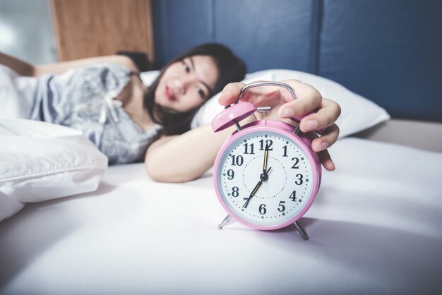 Gros plan sélectionnez l&#39;horloge de mise au point avec une belle femme dans la chambre