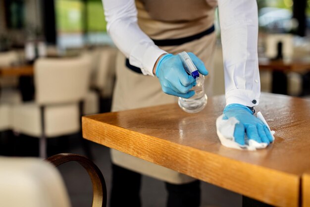 Gros plan sur un serveur désinfectant des tables de café après le travail
