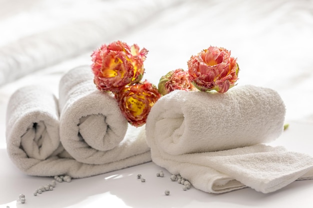 Gros plan des serviettes de bain en éponge blanche et des fleurs
