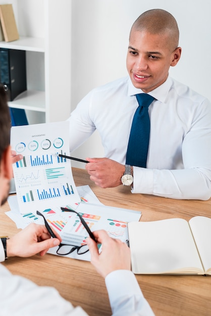 Gros plan, de, a, souriant, jeune homme affaires, projection, graphique, à, crayon, à, ses, partenaire, à, lieu de travail