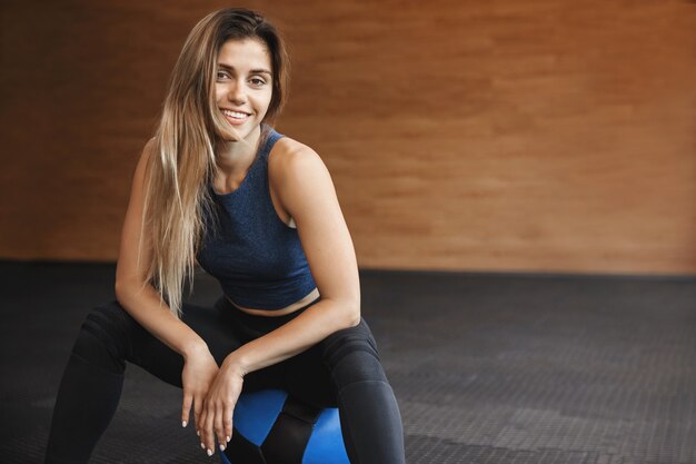 Gros plan d'une sportive souriante portant des vêtements de sport se trouve un médecine-ball.