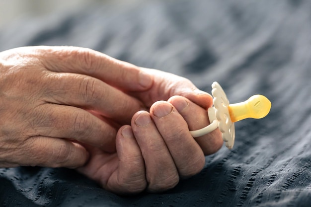 Photo gratuite gros plan sur une sucette pour bébé entre les mains d'une grand-mère