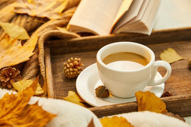 Gros plan d'une tasse de café et de feuilles d'automne sur une surface en bois
